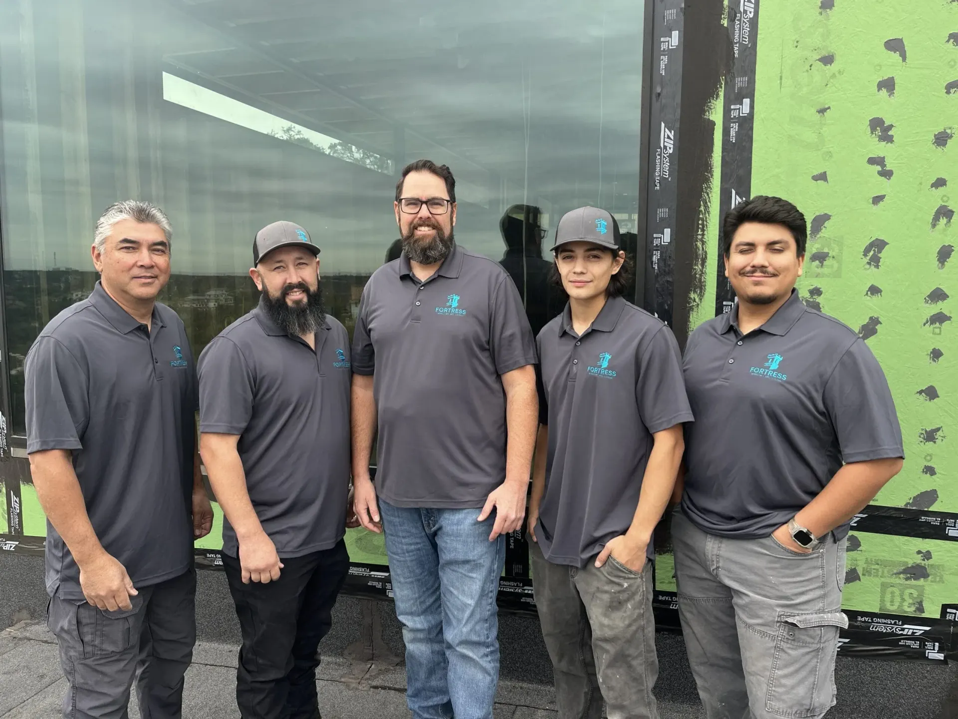 Five Fortress installation team members beside a large glass panel