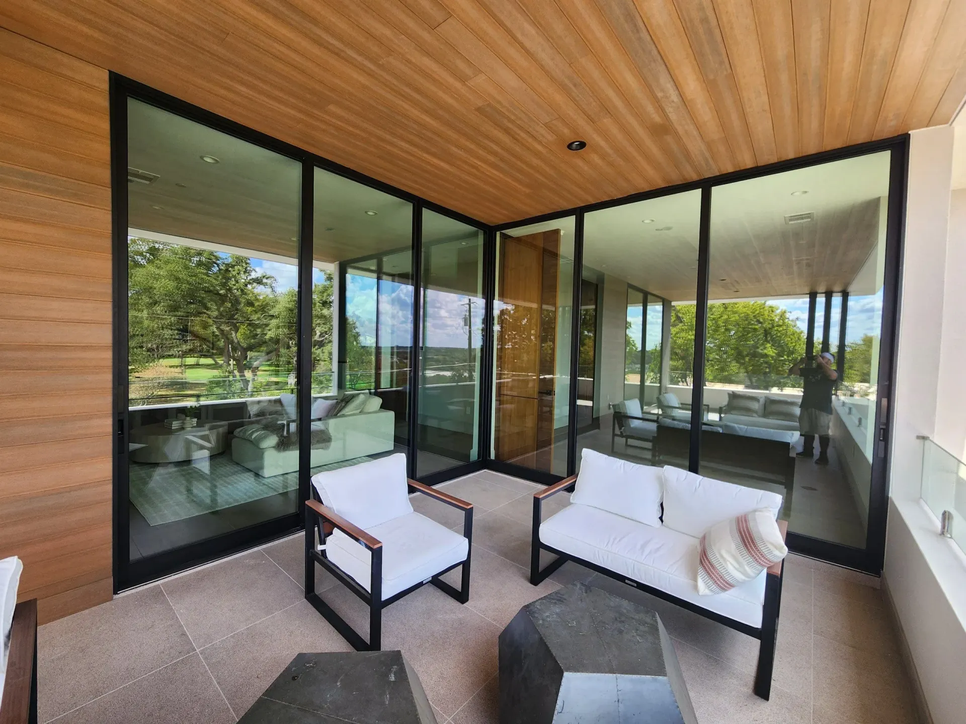 Armchairs on a covered balcony beside corner glass doors